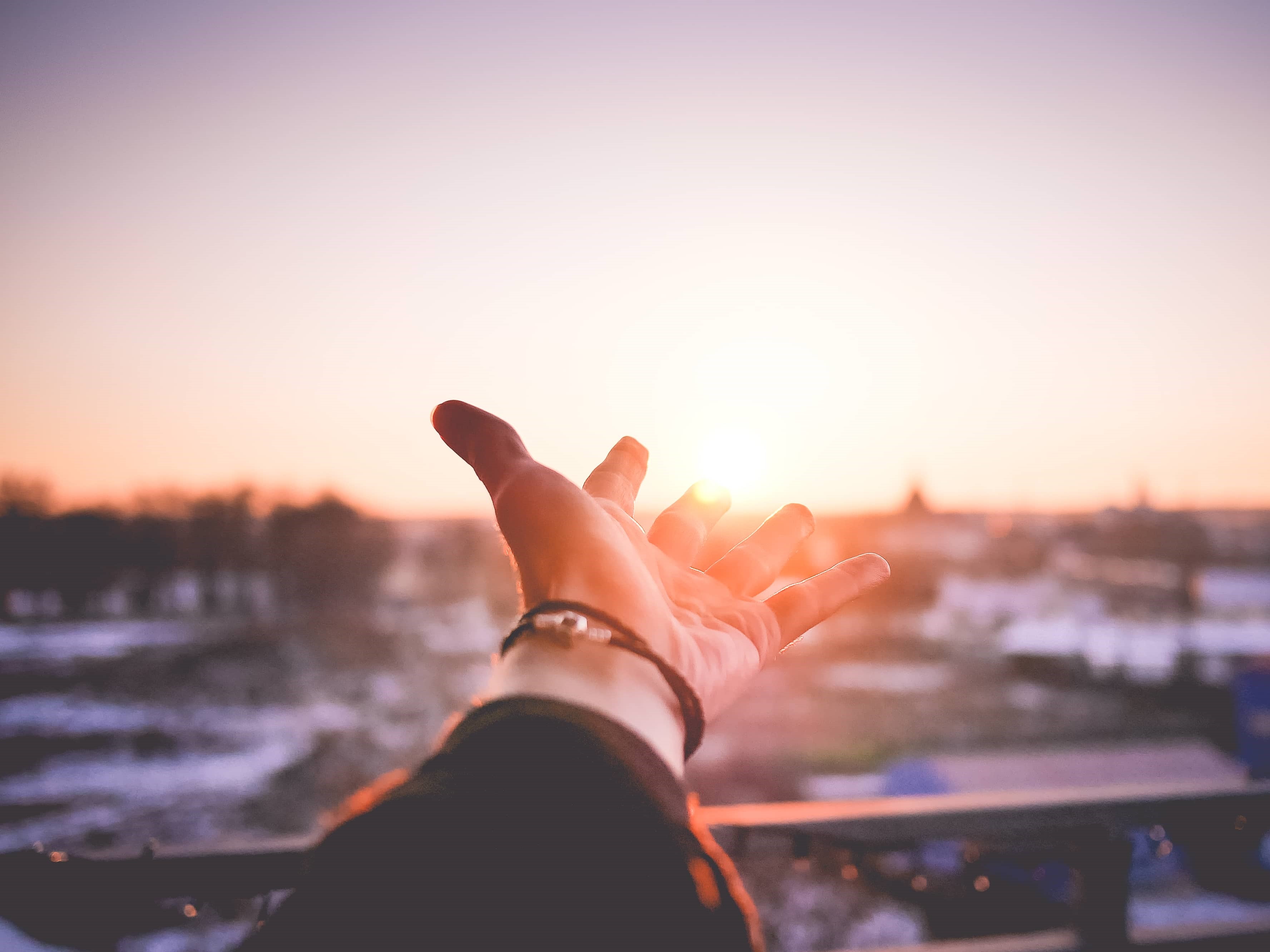 Une main est levée vers le soleil couchant