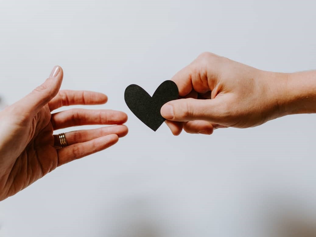 Une main tend un coeur à une autre main